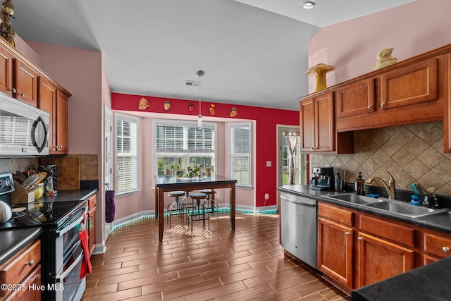 kitchen featuring visible vents, dark countertops, tasteful backsplash, a sink, and stainless steel appliances