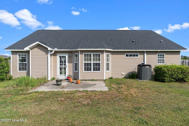 rear view of house with a patio, a lawn, central AC, and roof with shingles