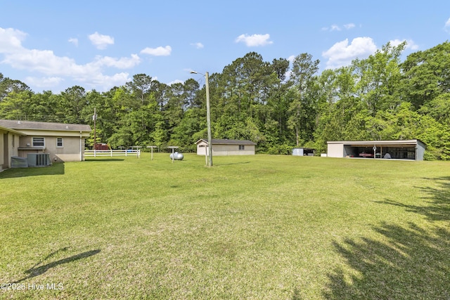 view of yard featuring fence, an outdoor structure, and central AC