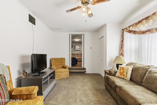 living area with crown molding, carpet flooring, baseboards, and a ceiling fan