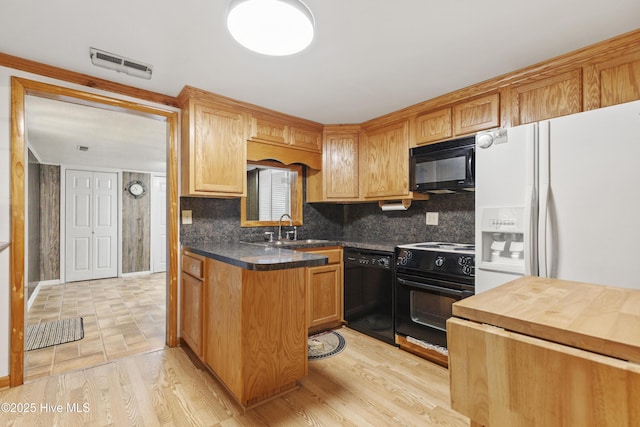 kitchen featuring backsplash, visible vents, a sink, black appliances, and light wood-style floors