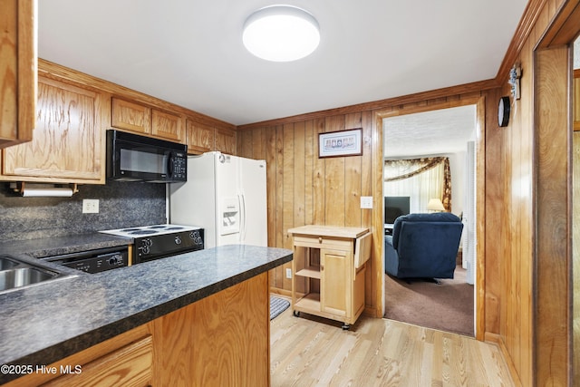 kitchen with wood walls, dark countertops, light wood-type flooring, tasteful backsplash, and black appliances