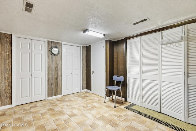 interior space featuring a textured ceiling, visible vents, and baseboards
