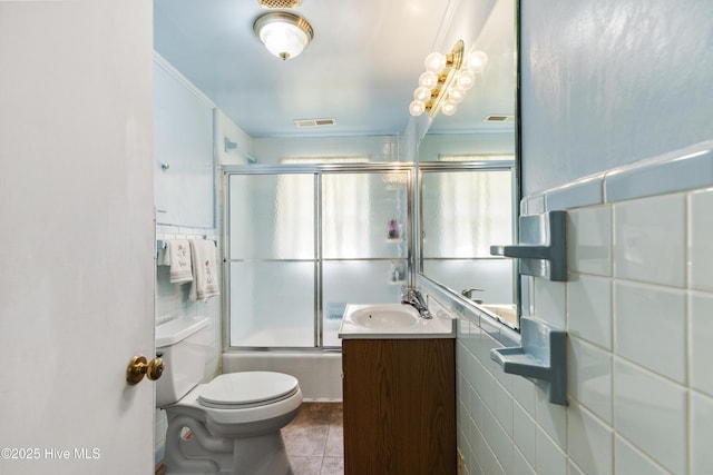 bathroom with enclosed tub / shower combo, toilet, tile walls, and visible vents