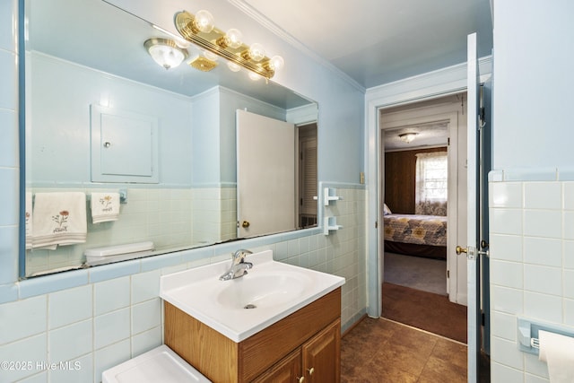 ensuite bathroom featuring tile patterned flooring, crown molding, vanity, tile walls, and ensuite bath