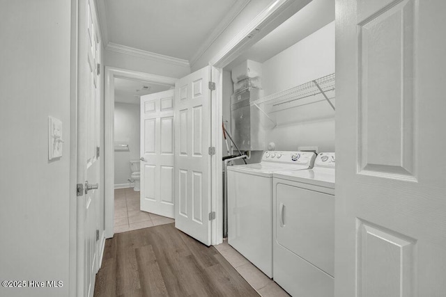 washroom with washing machine and clothes dryer, laundry area, crown molding, and wood finished floors