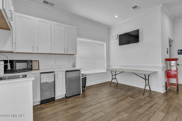 kitchen featuring a sink, light countertops, visible vents, and white cabinets