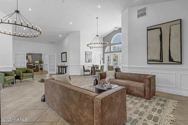 living area with a decorative wall, french doors, visible vents, an inviting chandelier, and light tile patterned floors