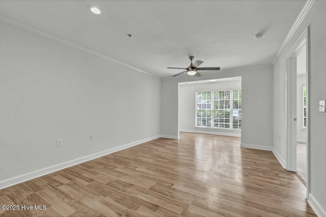 spare room featuring crown molding, light wood-style floors, baseboards, and a ceiling fan