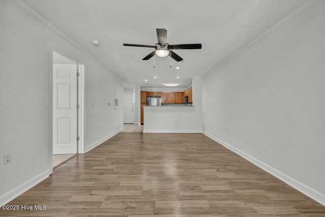 unfurnished living room featuring crown molding, light wood-style flooring, baseboards, and a ceiling fan