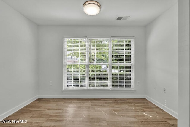 unfurnished dining area featuring baseboards, visible vents, and wood finished floors