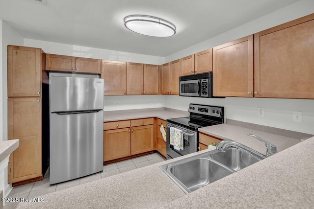 kitchen featuring light countertops, appliances with stainless steel finishes, light tile patterned floors, and a sink