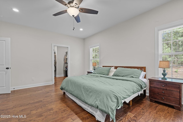 bedroom with recessed lighting, baseboards, a walk in closet, and wood finished floors