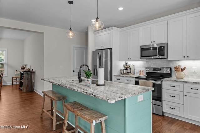 kitchen with decorative backsplash, white cabinetry, a sink, dark wood finished floors, and stainless steel appliances