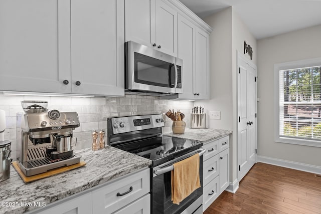 27 Pine Lake Dr, Whispering Pines, NC 28327 - kitchen with appliances with stainless steel finishes, dark wood finished floors, decorative backsplash, baseboards, and light stone countertops