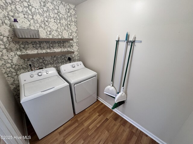 laundry room with baseboards, laundry area, washing machine and dryer, and wood finished floors