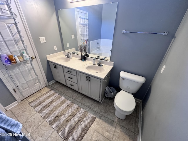 bathroom with a sink, baseboards, toilet, and double vanity