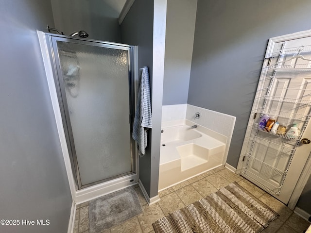 bathroom with baseboards, a stall shower, and a bath