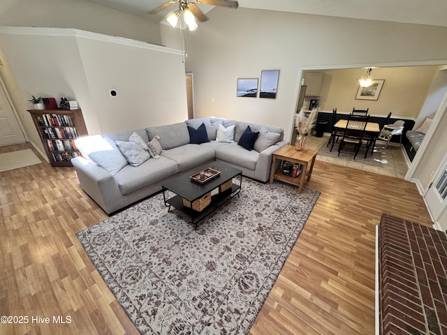 living area featuring a ceiling fan, high vaulted ceiling, and light wood finished floors