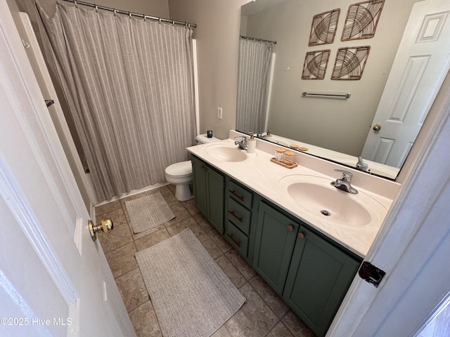 bathroom with double vanity, toilet, a sink, and tile patterned flooring