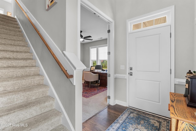 foyer entrance with dark wood finished floors, stairway, ceiling fan, and baseboards