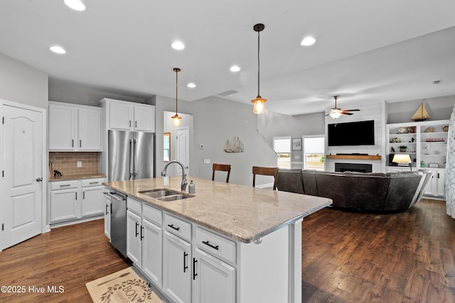 kitchen with appliances with stainless steel finishes, a sink, a ceiling fan, dark wood-style floors, and pendant lighting