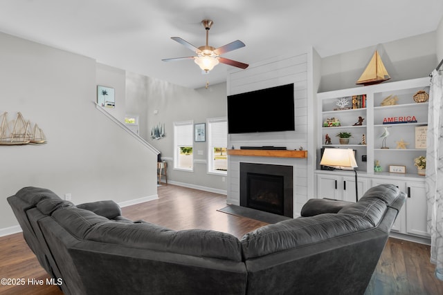 living area with a fireplace, a ceiling fan, dark wood-type flooring, and baseboards