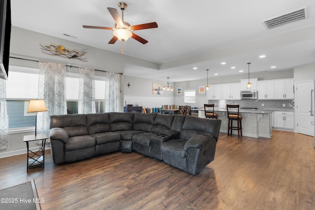living area featuring wood finished floors, ceiling fan, plenty of natural light, recessed lighting, and baseboards