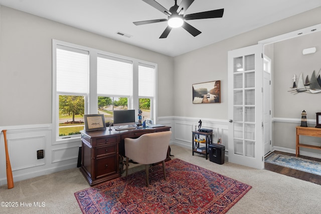 home office with light carpet, wainscoting, ceiling fan, a decorative wall, and french doors
