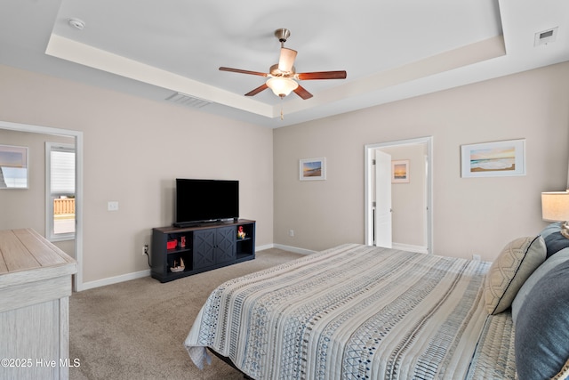 carpeted bedroom with a tray ceiling, baseboards, and a ceiling fan