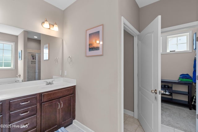 bathroom featuring plenty of natural light, tiled shower, baseboards, and vanity