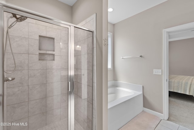 ensuite bathroom with a shower stall, a garden tub, tile patterned floors, and baseboards