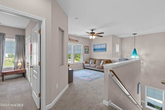 living area featuring carpet, a ceiling fan, and baseboards