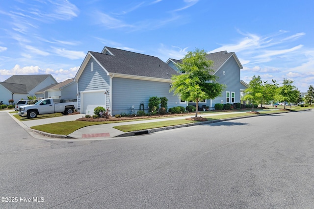 view of home's exterior with driveway, an attached garage, a shingled roof, and a lawn