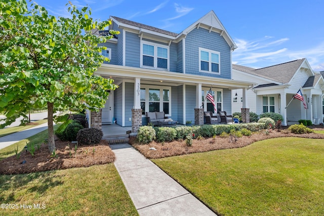 craftsman-style house with a front lawn, a porch, and roof with shingles