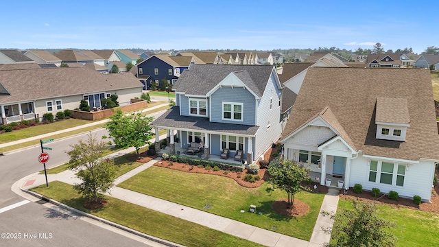 view of front of property with a residential view, a porch, a shingled roof, and a front yard