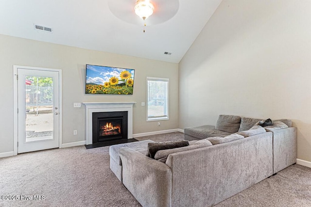 carpeted living room featuring visible vents, a fireplace with flush hearth, baseboards, and ceiling fan