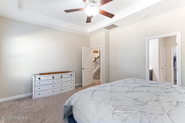 bedroom featuring a ceiling fan, visible vents, a raised ceiling, baseboards, and carpet