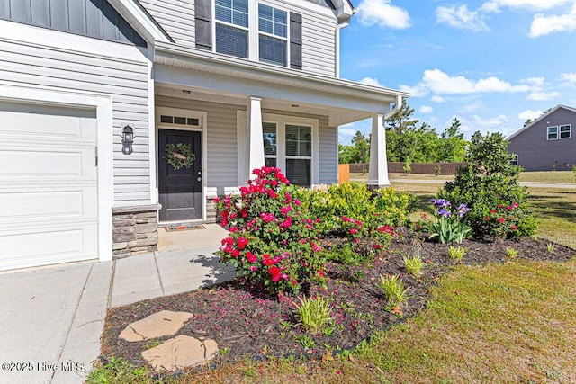 property entrance with a garage, board and batten siding, a porch, and stone siding