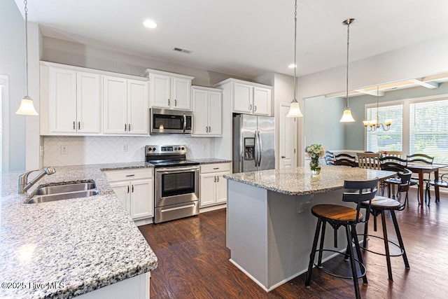 kitchen featuring visible vents, a kitchen bar, white cabinets, a sink, and appliances with stainless steel finishes