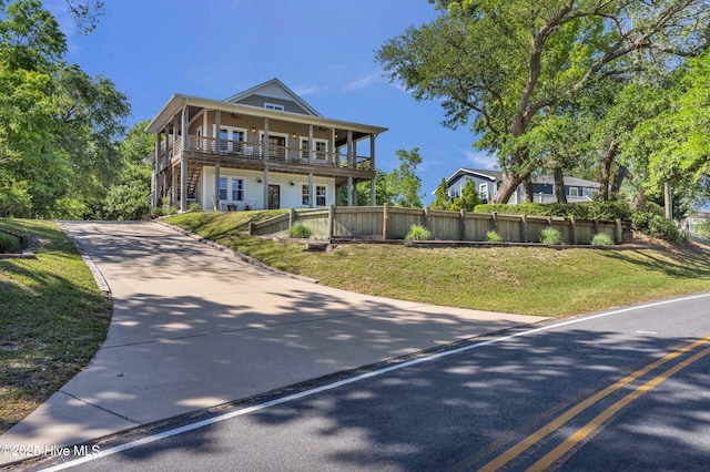 view of front of house featuring fence, driveway, a front lawn, and stairway