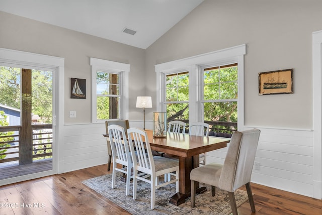 dining room featuring wood-type flooring, wainscoting, wood walls, and visible vents