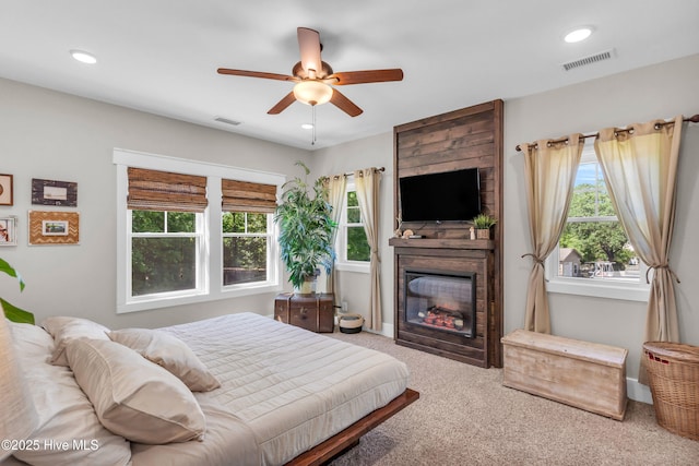 bedroom with carpet floors, a fireplace, a ceiling fan, and visible vents