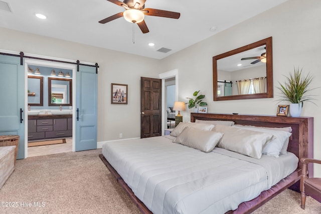 bedroom featuring light colored carpet, visible vents, a barn door, a sink, and recessed lighting