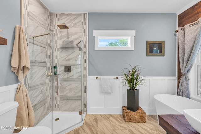 full bath with marble finish floor, wainscoting, a decorative wall, and a stall shower