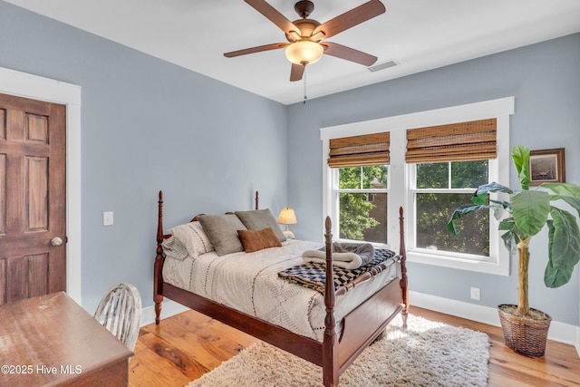 bedroom with a ceiling fan, baseboards, visible vents, and wood finished floors