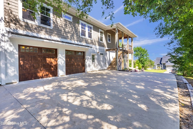 view of side of home featuring stairway, driveway, and a garage