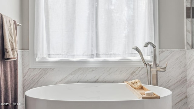 bathroom featuring tile walls, a soaking tub, and a wainscoted wall