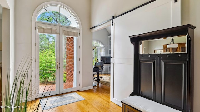 entryway with light wood-type flooring, a barn door, baseboards, and french doors