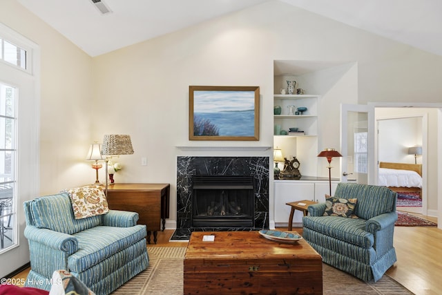 3733 Winstead Cir, Southport, NC 28461 - living room featuring visible vents, built in features, a fireplace, vaulted ceiling, and wood finished floors